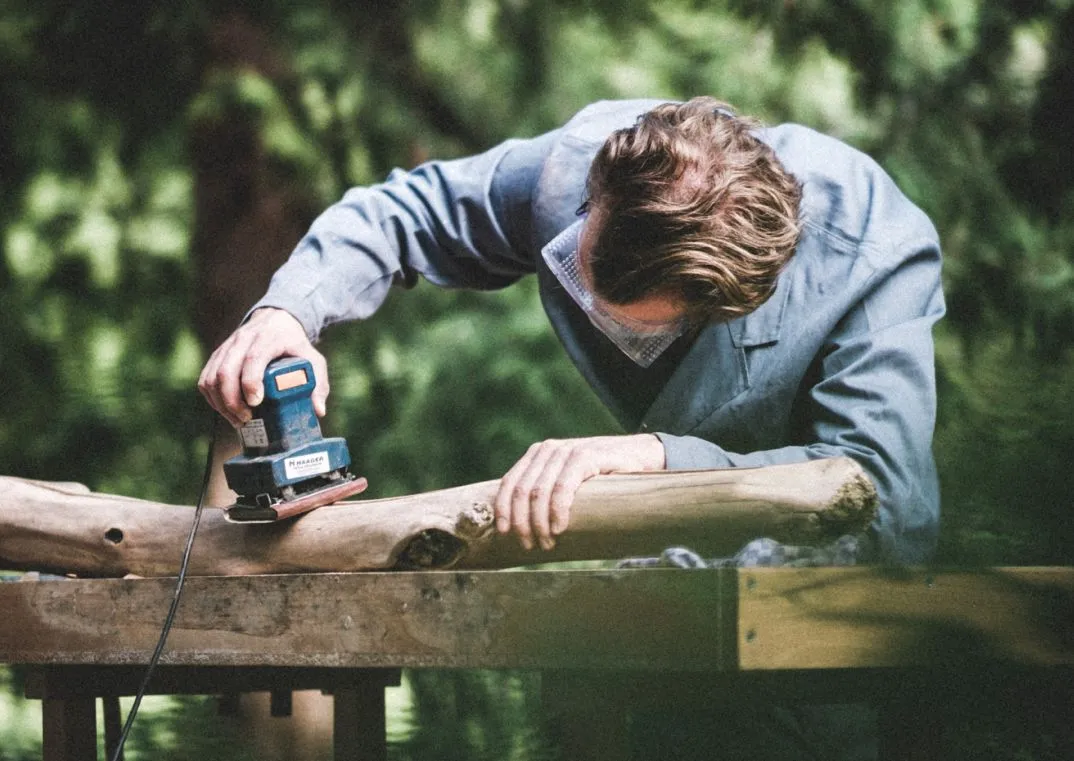 Sanding a piece of driftwood by hand in the workshop