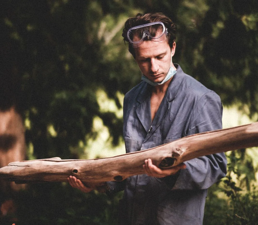 Inspecting a shaped piece of driftwood outdoors